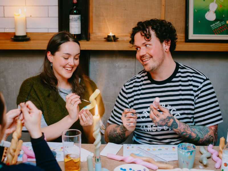 Smiling man and woman making and painting candles